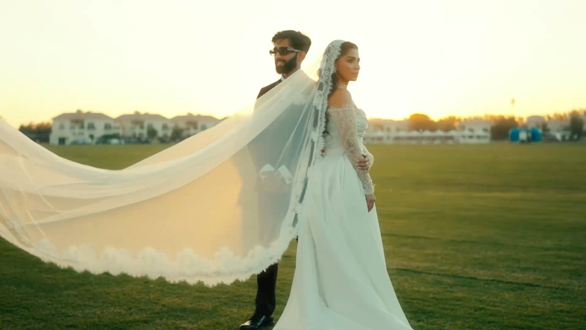A couple photographed at golden hour on the lawns, the bride’s veil drifting across the grass